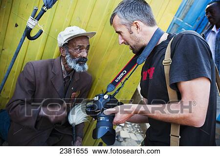 Stock Photography - Travelling photographer taking picture of elderly man; Ethiopia. Fotosearch