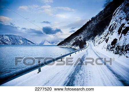 Treacherous icy road winding around the mountainside and Fjord shoreline with dramatic view of the mountains; Ortnevik, Sognefjord, Norway View Large Photo Image Stock Image - Treacherous icy road winding around the mountainside and Fjord shoreline with dramatic view of the mountains; Ortnevik, Sognefjord, Norway. Fotosearch