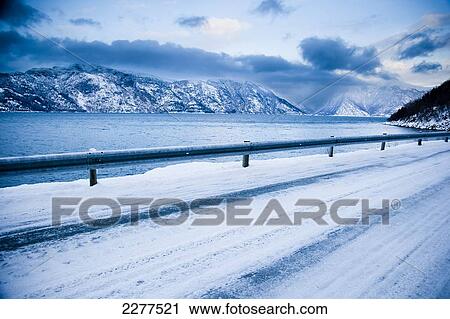 Treacherous icy road winding around the mountainside and Fjord shoreline with dramatic view of the mountains; Ortnevik, Sognefjord, Norway View Large Photo Image Stock Image - Treacherous icy road winding around the mountainside and Fjord shoreline with dramatic view of the mountains; Ortnevik, Sognefjord, Norway. Fotosearch