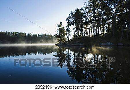 Tree Silhouette Reflections On Blindfold Lake In Northwestern Ontario; Ontario Canada View Large Photo Image Stock Photograph - Tree Silhouette Reflections On Blindfold Lake In Northwestern Ontario; Ontario Canada. Fotosearch