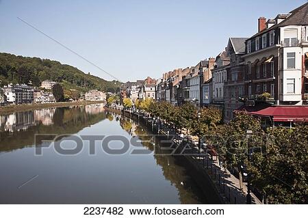 Stock Image - Trees And Buildings Reflected In The Tranquil River Meuse; Dinant Namur Belgium. Fotosearch