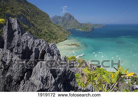 Tropical Island With Boats In The Distance; El Nido, Palawan, Philippines View Large Photo Image Stock Image - Tropical Island With Boats In The Distance; El Nido, Palawan, Philippines. Fotosearch