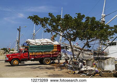 Truck laden with sacks by a Pinisi, a traditional two masted wooden cargo sailing ship moored in Paotere Harbour, Makassar (Ujung Pandang), South Sulawesi, Indonesia View Large Photo Image Stock Photo - Truck laden with sacks by a Pinisi, a traditional two masted wooden cargo sailing ship moored in Paotere Harbour, Makassar (Ujung Pandang), South Sulawesi, Indonesia. Fotosearch