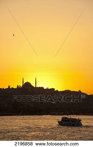 Stock Photo - Turkey, Ferry crossing Golden Horn with silhouette of Eyup Sultan mosque behind at dusk; Istanbul. Fotosearch