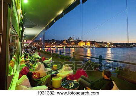 Stock Image - Turkey, Looking Along Line of Bars and Restaurants on Galata Bridge with Suleymaniye Mosque Behind at Dusk; Istanbul. Fotosearch