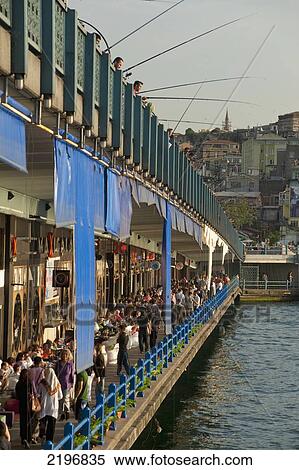 Stock Photography - Turkey, Looking along line of bars and restaurants on Galata Bridge with fishermen above; Istanbul. Fotosearch