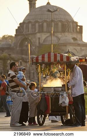 Stock Photo - Turkey, Sweetcorn seller in square beside Egyptian Bazaar with Suleymaniye Mosque behind at dusk; Istanbul. Fotosearch