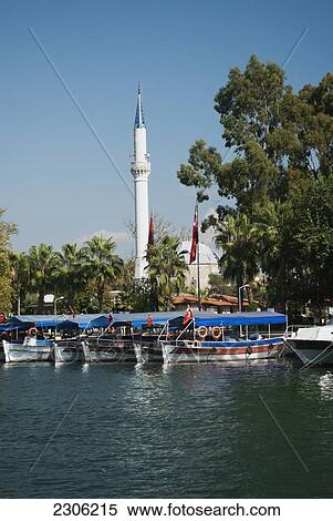 Stock Photography - Turkey, Western Mediteranean, Dalyan, Tourist boats along shore in front of minaret. Fotosearch