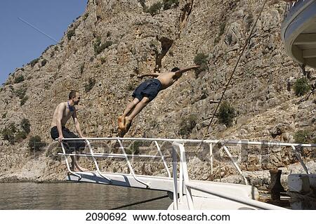 Stock Image - Turkish Youths Take Turns To Jump From A Pleasure Cruise Boat From Oludeniz In Butterfly Bay, The Turquoise Coast, Southern Turkey. Fotosearch