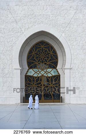 Stock Photo - Two Arab Men Walking Through Courtyard Of The Sheikh Zayed Grand Mosque, Abu Dhabi, United Arab Emirates. Fotosearch