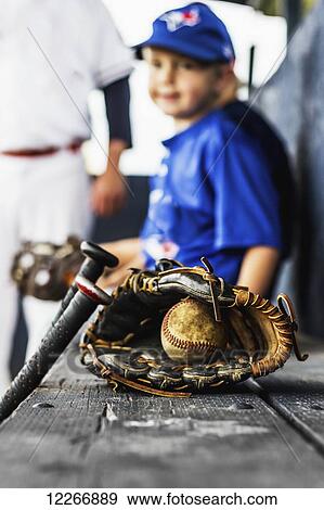 Two ball players in uniform sit in the dugout with their glove and baseball in focus in the foreground; Fort McMurray, Alberta, Canada View Large Photo Image Stock Photo - Two ball players in uniform sit in the dugout with their glove and baseball in focus in the foreground; Fort McMurray, Alberta, Canada. Fotosearch