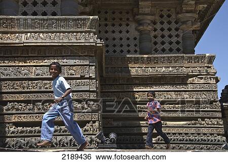 Two Boys Running In Front Of Ornate Carvings On Halebid Temple, Halebid, Karnataka, India View Large Photo Image Stock Photograph - Two Boys Running In Front Of Ornate Carvings On Halebid Temple, Halebid, Karnataka, India. Fotosearch