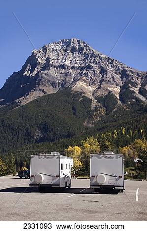 Stock Image - Two Camper Vans In Parking Lot In Front Of Mountain; British Columbia, Canada. Fotosearch