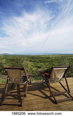 Stock Photograph - Two Deck Chairs On Wooden Deck Overlooking Grassland. Fotosearch