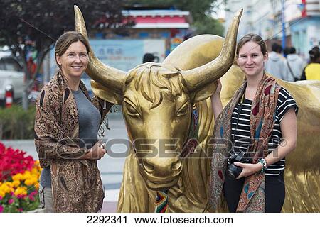 Two female tourists posing beside statue of golden cow; Lhasa, Xizang, China View Large Photo Image Stock Image - Two female tourists posing beside statue of golden cow; Lhasa, Xizang, China. Fotosearch