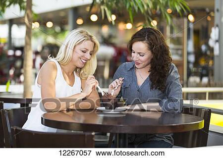 Stock Photo - Two girlfriends having dessert in a cafe after shopping; St. Albert, Alberta, Canada. Fotosearch
