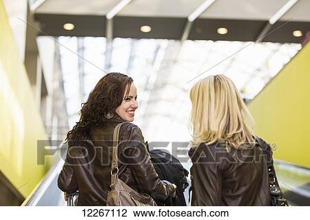 Stock Image - Two girlfriends out shopping together and taking the escalator; St. Albert, Alberta, Canada. Fotosearch