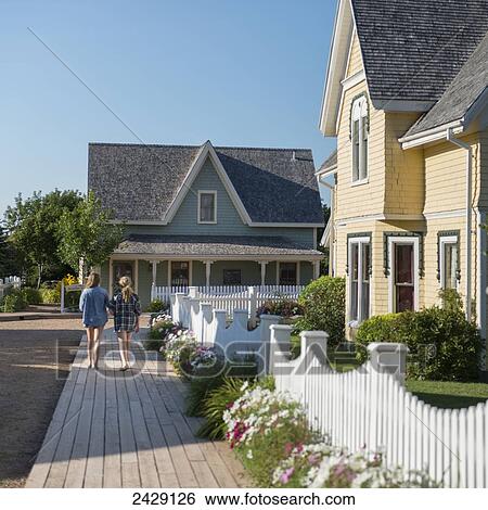 Stock Photograph - Two girls walk down a residential street with quaint houses and blue sky; Green Gables, Prince Edward Island, Canada. Fotosearch