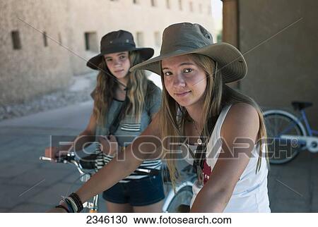 Two Girls Wearing Sun Hats And Sitting On Bikes; China View Large Photo Image Stock Image - Two Girls Wearing Sun Hats And Sitting On Bikes; China. Fotosearch