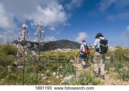 Stock Image - Two Hikers On Track Towards Teix Peak. Fotosearch