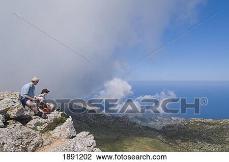 Two Hikers Sitting On Texi Mountain Peak, Looking At View, Side View View Large Photo Image Stock Image - Two Hikers Sitting On Texi Mountain Peak, Looking At View, Side View. Fotosearch