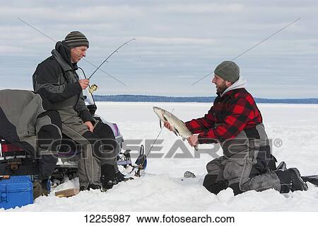 Stock Photo - Two ice fishermen, one holding a large whitefish; Ontario, Canada. Fotosearch