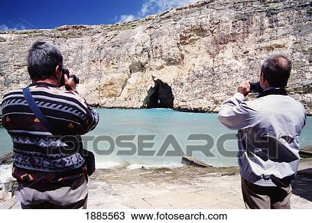 Stock Image - Two Men Videoing A Cave. Fotosearch