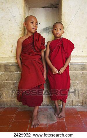 Stock Image - Two novice monks standing in a Buddhist monastery, Upper Burma; Myanmar. Fotosearch