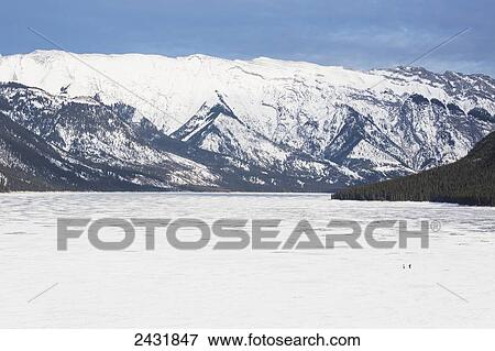 Two people in the distance crossing Lake Minnewanka after playing hockey on exposed ice surface, Banff National Park; Alberta, Canada View Large Photo Image Stock Photo - Two people in the distance crossing Lake Minnewanka after playing hockey on exposed ice surface, Banff National Park; Alberta, Canada. Fotosearch