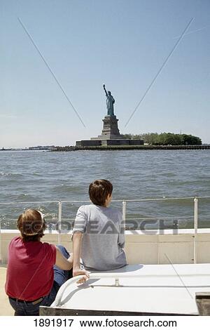 Stock Photo - Two People On Boat, Looking At Statue Of Liberty. Fotosearch