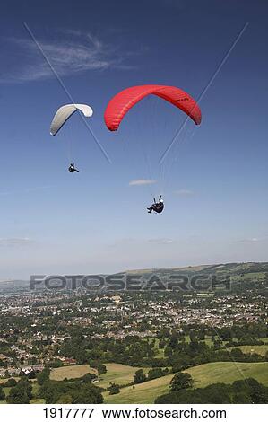 Stock Photo - Two People Paragliding Over Cotswolds Escarpment Above National Trail. Fotosearch
