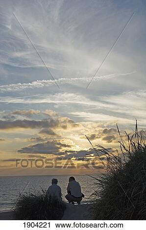 Two People Watching Sunset On Beach, Ear View, Jutland, Denmark View Large Photo Image Stock Image - Two People Watching Sunset On Beach, Ear View, Jutland, Denmark. Fotosearch