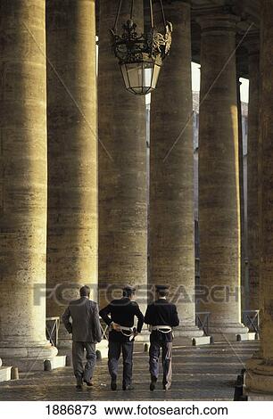 Stock Image - Two Police And Man Walking Beside Colonnade In St Peters Square. Fotosearch