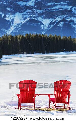 Two red chairs on snow covered ridge overlooking frozen lake with snow covered mountain cliff in the background; Banff, Alberta, Canada View Large Photo Image Stock Photo - Two red chairs on snow covered ridge overlooking frozen lake with snow covered mountain cliff in the background; Banff, Alberta, Canada. Fotosearch