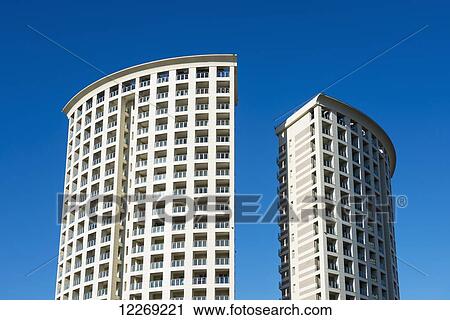 Stock Image - Two rounded residential buildings side by side against a blue sky; Genoa, Liguria, Italy. Fotosearch