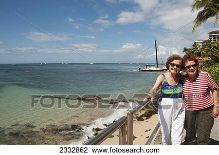 Two Sisters Posing Along The Shoreline, Waikiki Beach; Oahu, Hawaii, United States Of America View Large Photo Image Stock Image - Two Sisters Posing Along The Shoreline, Waikiki Beach; Oahu, Hawaii, United States Of America. Fotosearch