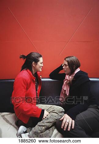 Stock Image - Two Sisters Talking On A Sofa. Fotosearch