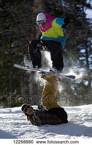 Stock Image - Two snowboarders have fun doing a balance trick in the snow; Utah, United States of America. Fotosearch