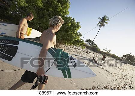 Two Surfers Carrying Surfboards On Beach View Large Photo Image Stock Image - Two Surfers Carrying Surfboards On Beach. Fotosearch