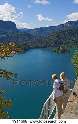 Stock Photo - Two Tourists Looking At Lake Bled From Castle Terrace. Fotosearch