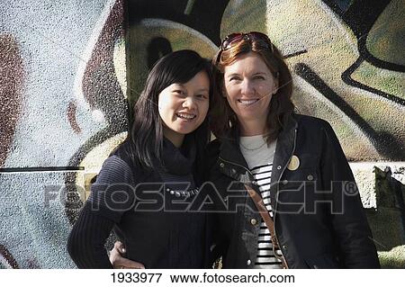 Stock Photo - Two Woman Posing In Front Of Mural; Beijing, China. Fotosearch