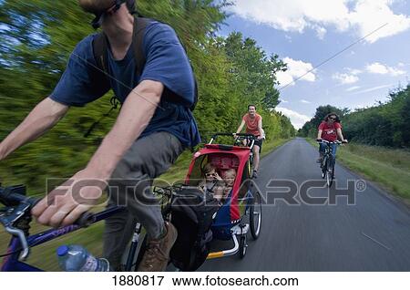 Two Women And Man Cycling With Chariot With Two Young Children (8-9) View Large Photo Image Stock Photo - Two Women And Man Cycling With Chariot With Two Young Children (8-9). Fotosearch