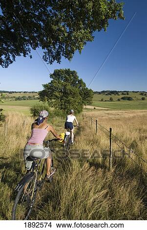 Two Women Cycling Down Bridle Path Through Meadow View Large Photo Image Picture - Two Women Cycling Down Bridle Path Through Meadow. Fotosearch