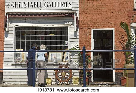 Stock Image - Two Women Looking Into A Gallery In Whitstable, Kent, England, United Kingdom. Fotosearch