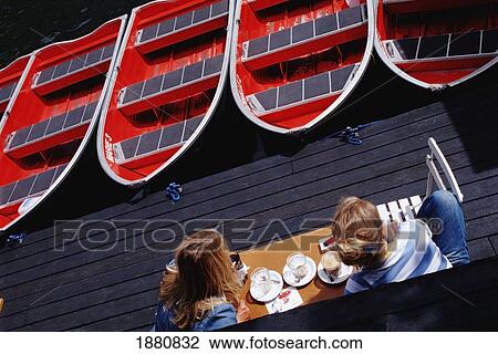 Stock Image - Two Women Sitting In A Cafe Next To The River. Fotosearch