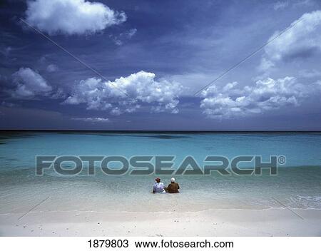 Stock Image - Two Women Sitting In Shallow Water. Fotosearch