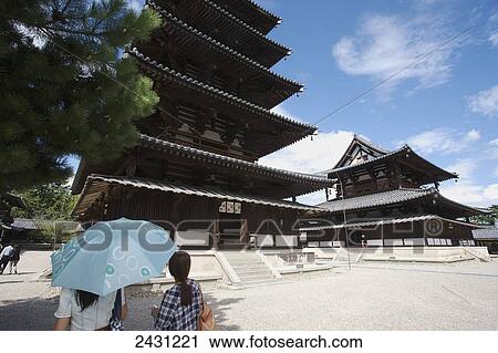 Stock Image - Two women stand outside a pagoda; Japan. Fotosearch