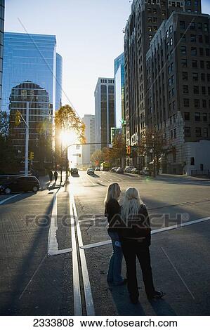 Two Women Standing In Street During Sunset, Downtown; Vancouver, British Columbia, Canada View Large Photo Image Stock Photo - Two Women Standing In Street During Sunset, Downtown; Vancouver, British Columbia, Canada. Fotosearch
