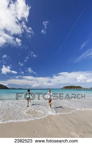 Two young girls run through the water on Cinnamon beach in the Virgin Islands; United States of America View Large Photo Image Stock Image - Two young girls run through the water on Cinnamon beach in the Virgin Islands; United States of America. Fotosearch