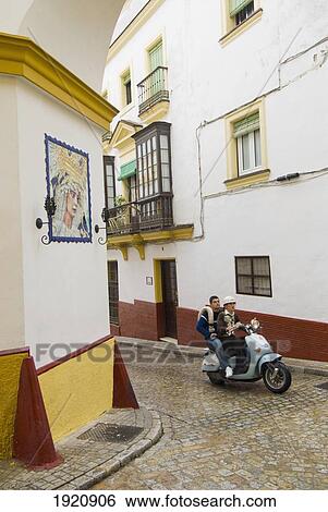 Two Young Men On Moped Passing Virgin Mary Ceramic On House Wall In Alley Of Jerez, Andalucia, Spain View Large Photo Image Stock Photograph - Two Young Men On Moped Passing Virgin Mary Ceramic On House Wall In Alley Of Jerez, Andalucia, Spain. Fotosearch